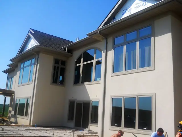 Finished two-story concrete home with stucco exterior and large windows