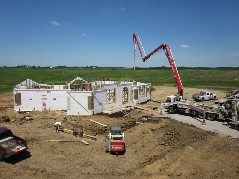 Concrete pump truck filling ICF walls on a new home site in open farm country