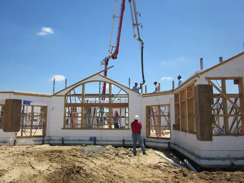 ICF walls going up with arched window bucks and a concrete pump boom overhead